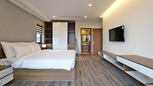 Une chambre d’hôtel moderne dotée d’un grand lit, d’une télévision, d’un dressing et d’une salle de bain.