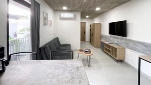 Ein modernes Wohnzimmer mit einer Couch, einem Esstisch und einem an der Wand befestigten Fernseher.