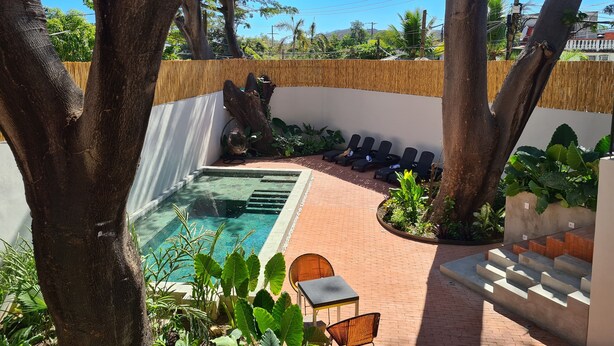 Ein Poolbereich mit Liegestühlen, einem kleinen Tisch und Treppen zum Pool.