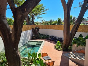 Un espace piscine aménagé avec des chaises longues, une petite table et des marches menant à la piscine.