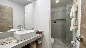 Un baño moderno con un espejo grande, dos lavamanos, una ducha y un inodoro.