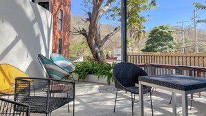 Eine Außenpatio mit Pergola, Sitzgruppe und Blick auf ein rotes Gebäude und Bäume.