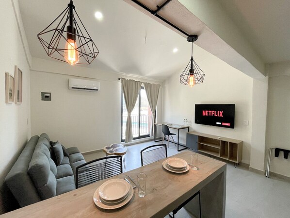 A modern living room with a sofa, dining table, and TV. - Rooms Huatulco (Santa María Huatulco)