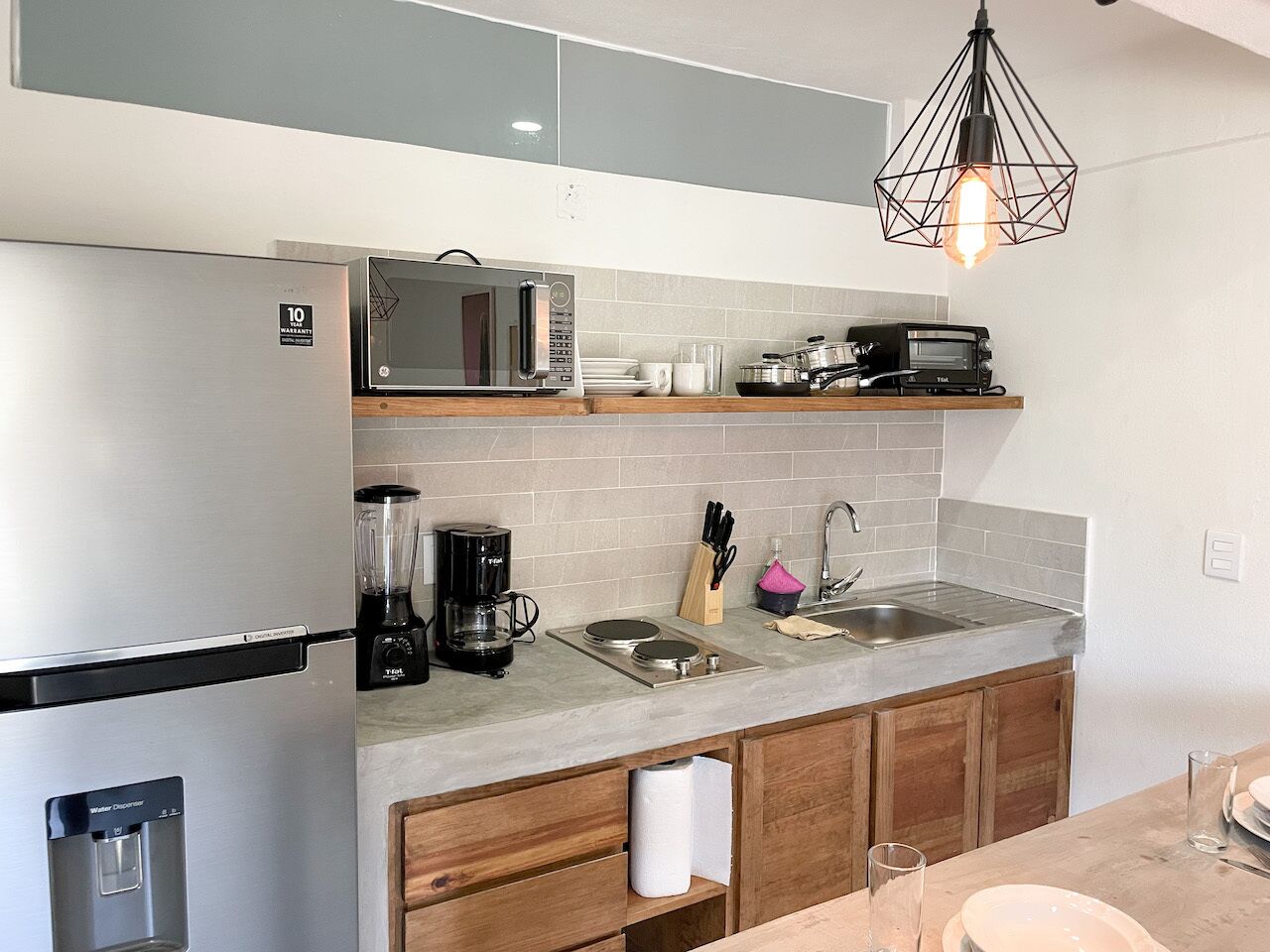 A modern kitchen with a built-in microwave, coffee maker, and a sink.