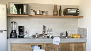 Eine Küche mit Mikrowelle, Toaster, Mixer und Spüle. Außerdem Obst und ein Schild mit der Aufschrift 'BE HAPPY'.