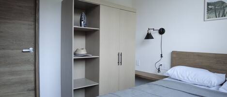 Une chambre à coucher comprenant un lit, une armoire, un bureau et une lampe fixée au mur.