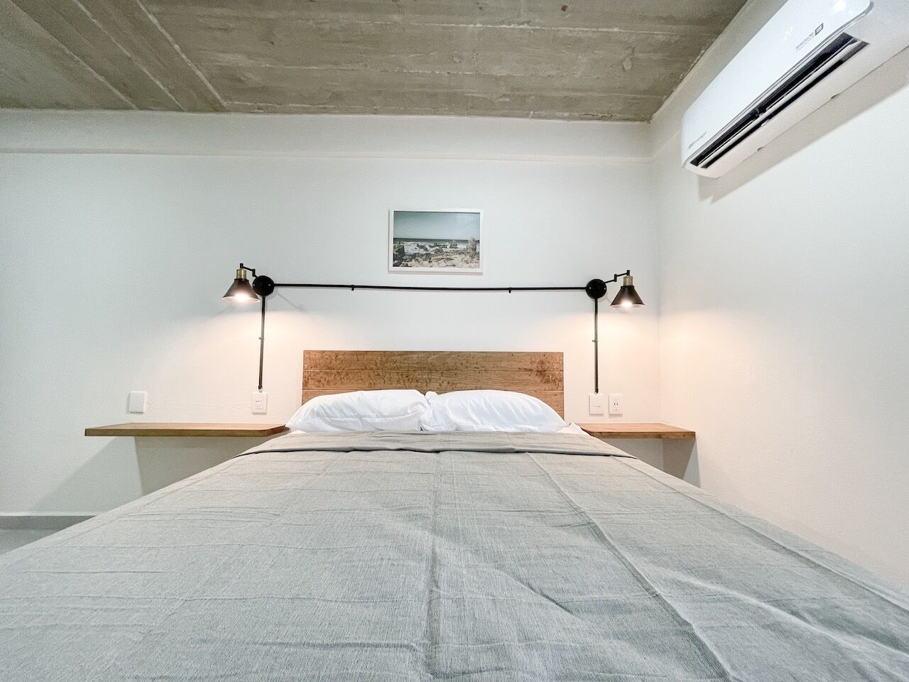 Ein schlicht eingerichtetes Schlafzimmer mit einem großen Bett, zwei Nachttischen und einem Holzkopfende.