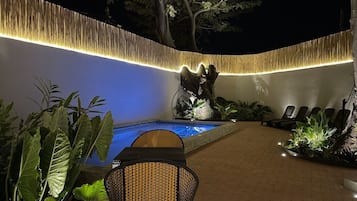 An outdoor pool area with a seating arrangement and a decorative wall.