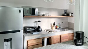 Eine moderne Küche mit einem Edelstahl-Kühlschrank, einer Mikrowelle, einem Toaster, einer Kaffeemaschine und einem Wasserspender.