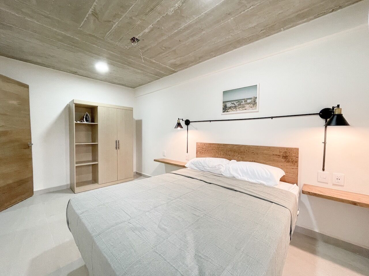 A bedroom with a bed, wooden wardrobe, and bedside lamps.