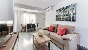 A modern living room with a beige sofa, a wooden coffee table, and a dining area with a table and chairs.