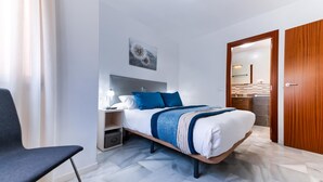 A modern bedroom with a bed, bedside table, lamp, and a chair.