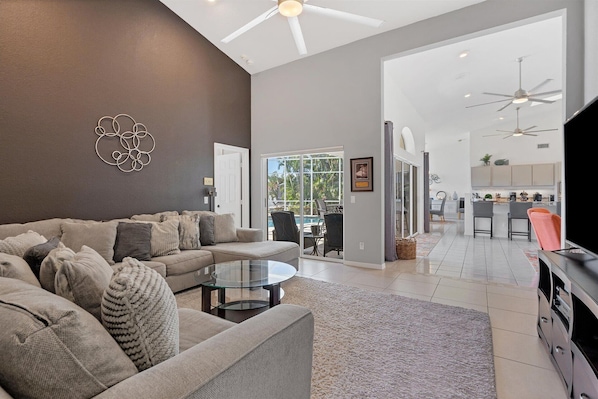 A spacious living room with a modern sofa, a glass coffee table, and a view of the outdoor patio. - Punta Gorda Isles 3-Bedroom Private Pool Home on Canal with Dock (Punta Gorda)