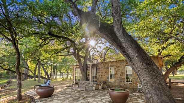 A stone building with a patio, surrounded by trees.