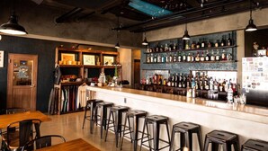 A bar with a long counter, multiple stools, and shelves of bottles. - MARINX POOLVILLA NAKANDAKARI (Nanjo)