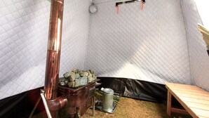 A tent interior with a wood stove, a table, and a hanging rack. - MARINX POOLVILLA NAKANDAKARI (Nanjo)