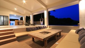 A modern living area with a large sofa, a wooden coffee table, and a kitchen in the background. - MARINX POOLVILLA NAKANDAKARI (Nanjo)