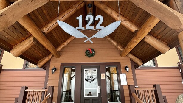 A wooden staircase leading to a door with the number 122 and an eagle symbol above it. - Best ski-in/ ski-out with A/C and fireplace! (Mont-Tremblant)