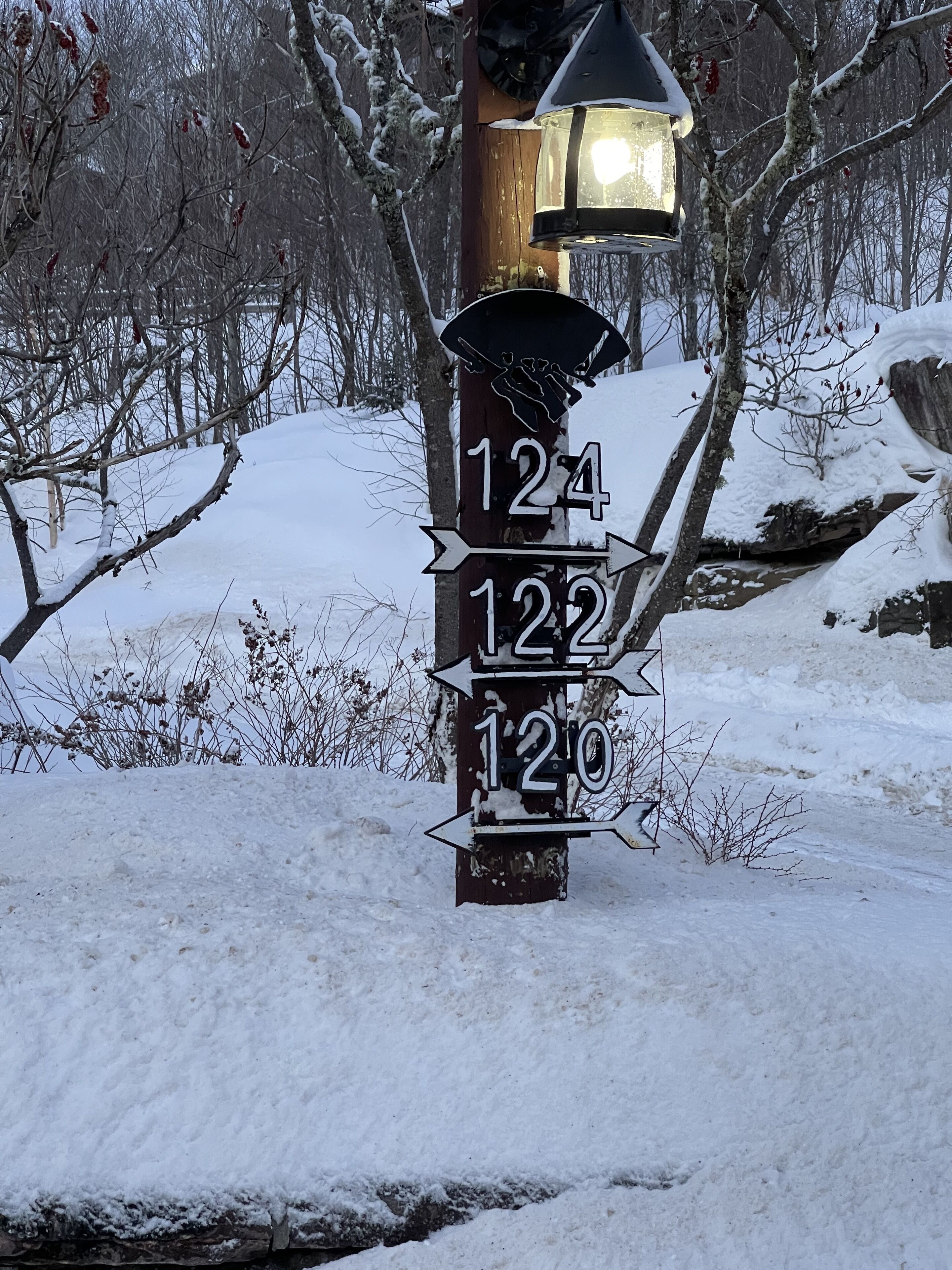 A wooden post with directional signs and a lantern.