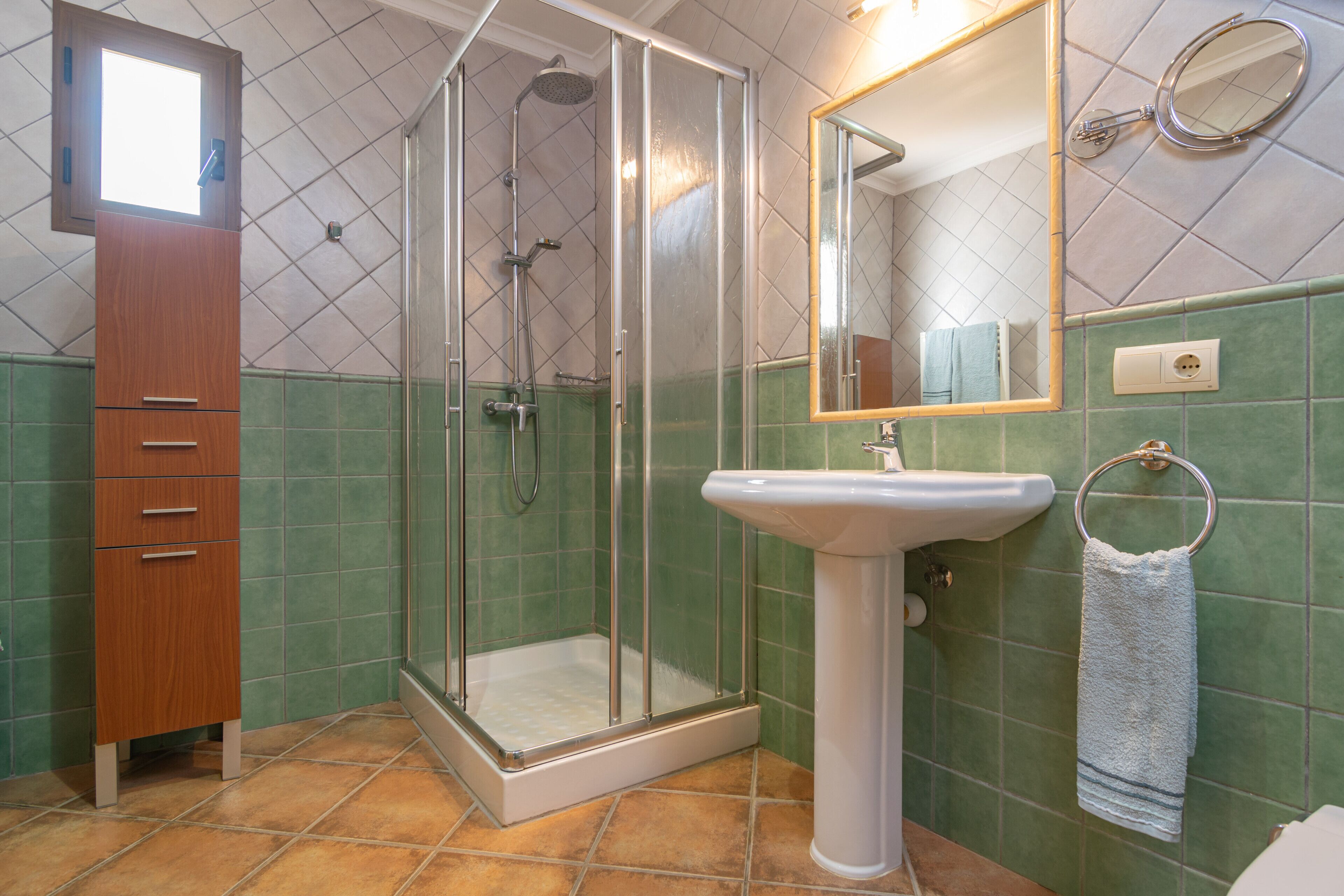A bathroom with a glass-enclosed shower, a sink, and a mirror.