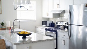 A modern kitchen with white cabinets, stainless steel appliances, a marble countertop, and a bowl of lemons. - 101, Ocean Side, Laundry, Desk, Backyard (South Padre Island)
