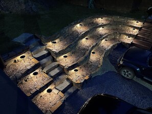 A stone fire pit with seating and a vehicle parked nearby.