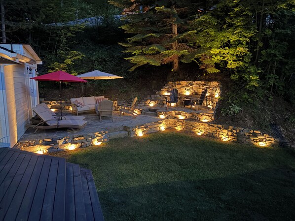 An outdoor patio area with stone seating, a wooden deck, and a small pool.
