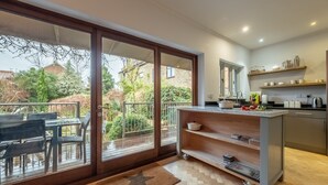 A modern kitchen with a sliding glass door leading to a balcony, a built-in shelf with kitchenware, and a star-patterned rug on the floor. - The Roundhouse, Wells-next-the-Sea, Norfolk (Wells-next-the-Sea)
