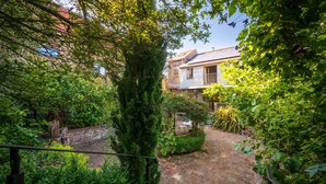 A courtyard with a brick pathway, lush greenery, and a building with a sloped roof. - The Roundhouse, Wells-next-the-Sea, Norfolk (Wells-next-the-Sea)