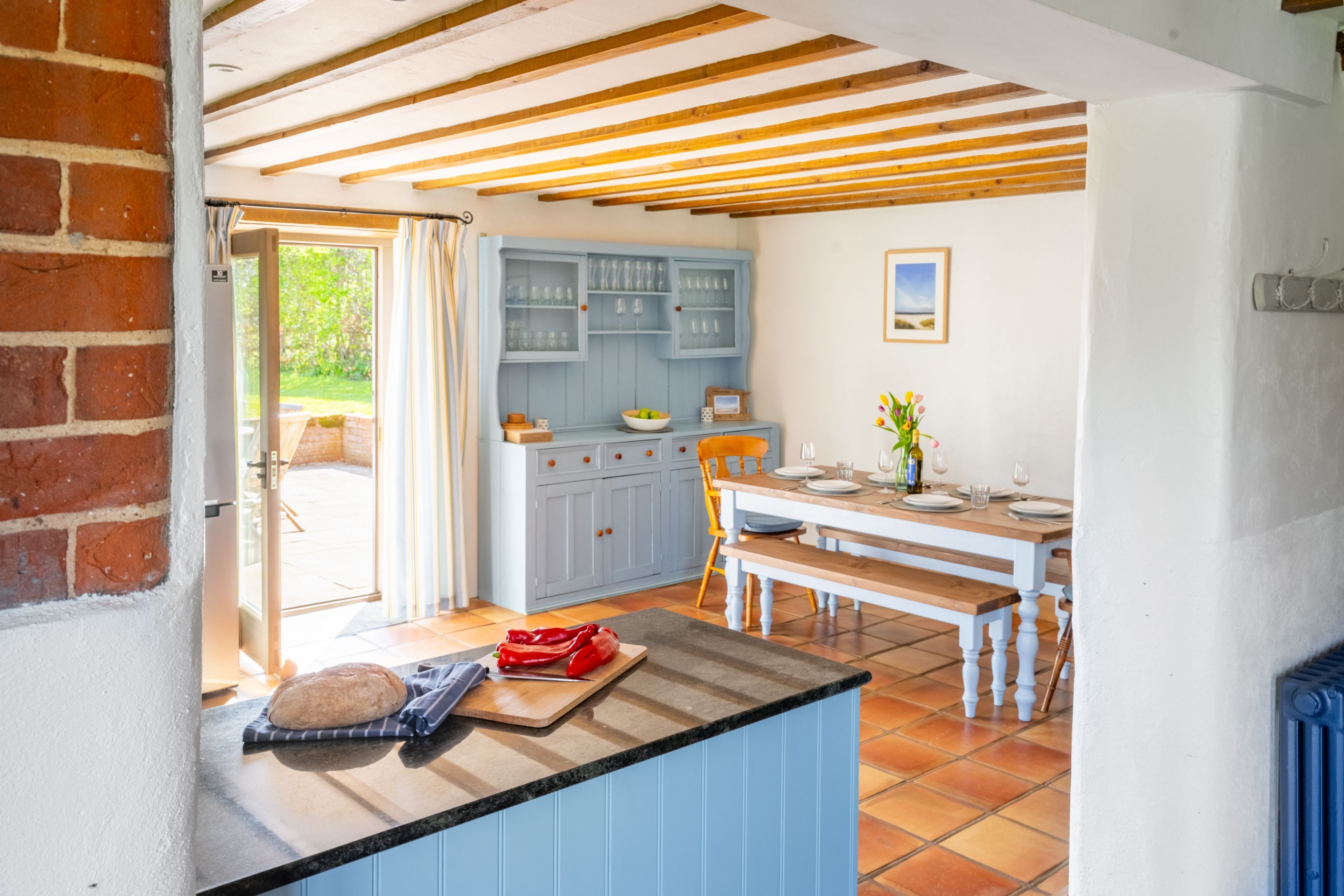 A kitchen with a wooden bench, a blue cabinet, and a dining table set for four.