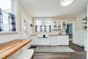 A modern kitchen with white cabinets, a wooden countertop, and a built-in oven.