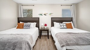 A hotel room with two beds, a nightstand, a ceiling fan, and decorative wall art. - Price Drop! Entire 4BR[10% OFF]Home| Wi-Fi & More-MD (Cypress)