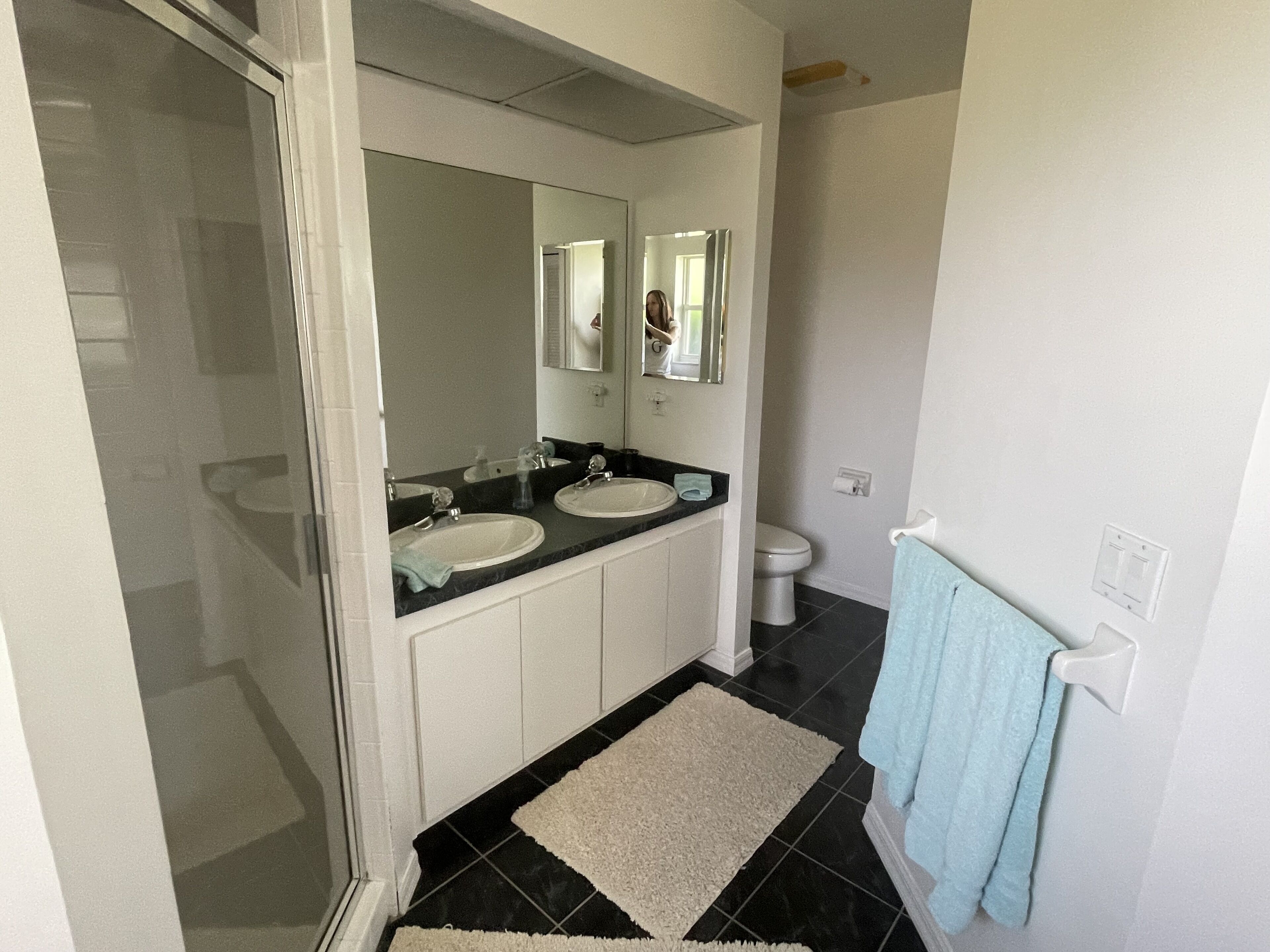 Ein Badezimmer mit zwei Waschbecken, einer Toilette, einer Dusche und einem Handtuchhalter.