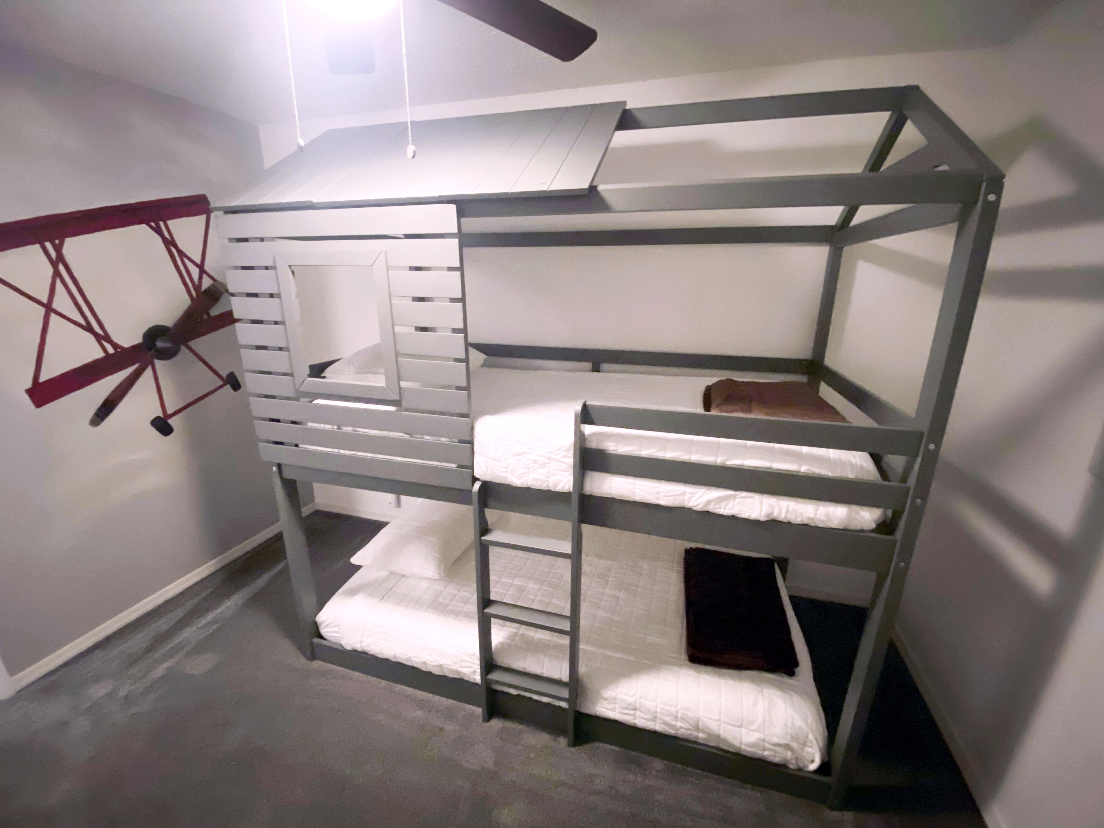 A bunk bed with a ladder, a small enclosed space, and a ceiling fan.