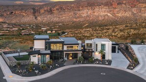 A modern two-story house with a flat roof, large windows, and a landscaped front yard with rocks and plants. - Eleanor at Copper Rock Golf Course, Private Pool, 2 Hot Tubs, Basketball Court, and more (Hurricane)
