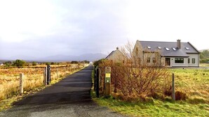 Una strada di campagna che conduce a una casa con cortile recintato e cancello.