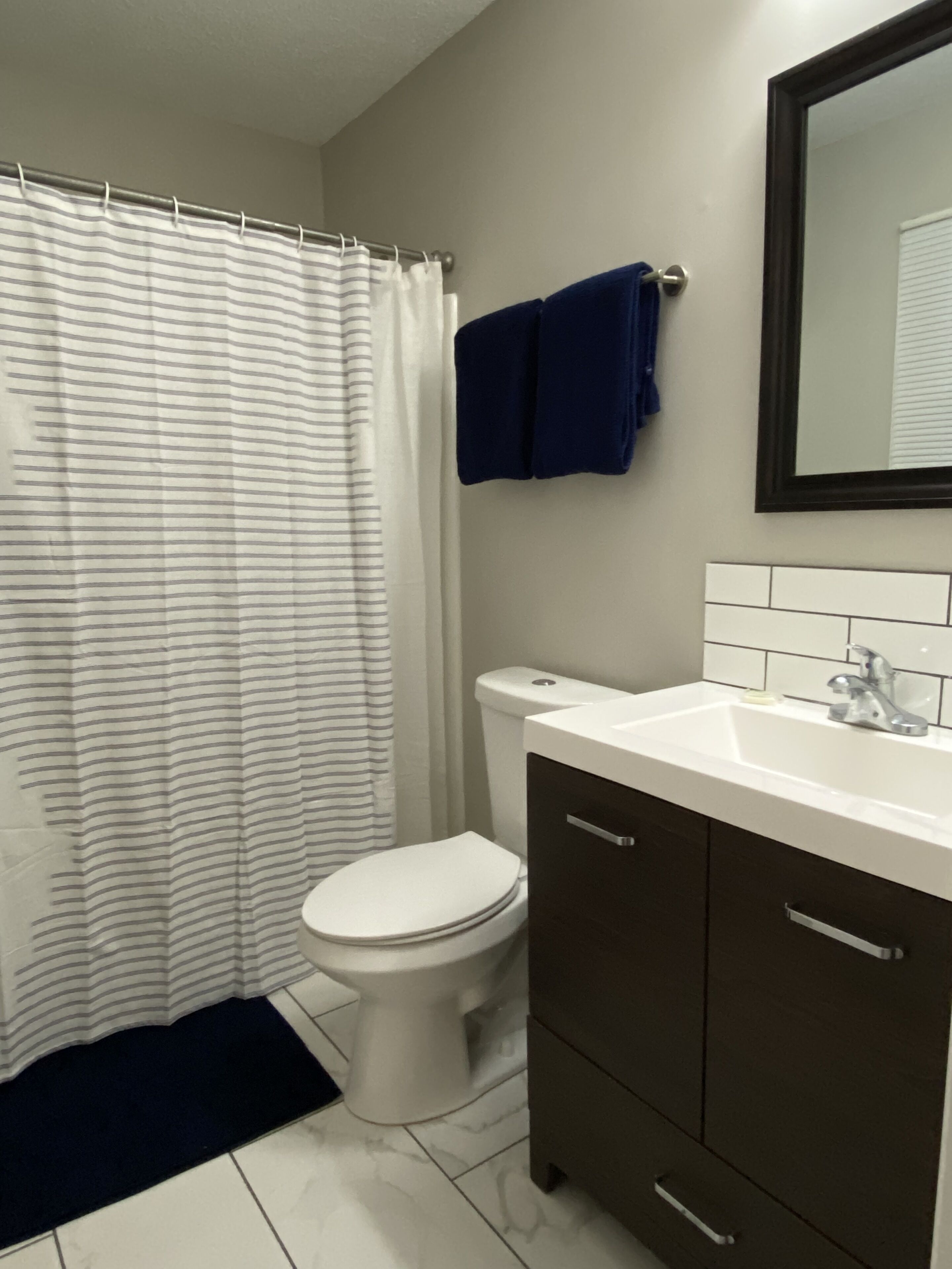 Un baño con inodoro blanco, lavamanos blanco con grifo plateado y un mueble de madera marrón oscuro.