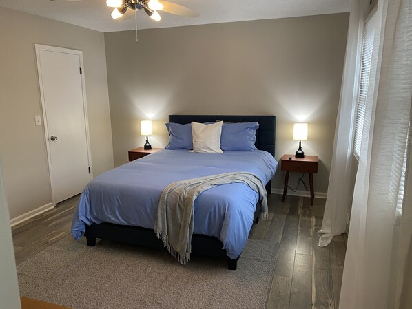 A bedroom with a bed, two bedside tables, a ceiling fan, and a door. - 3 bed 2 bath single level home in Kernersville (Kernersville)