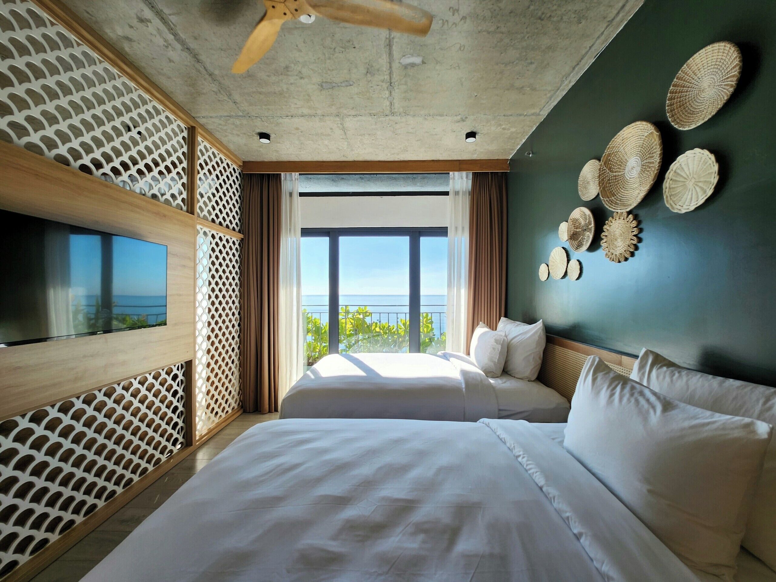 Een moderne hotelkamer met een groot bed, een televisie en een balkon met uitzicht op zee.
