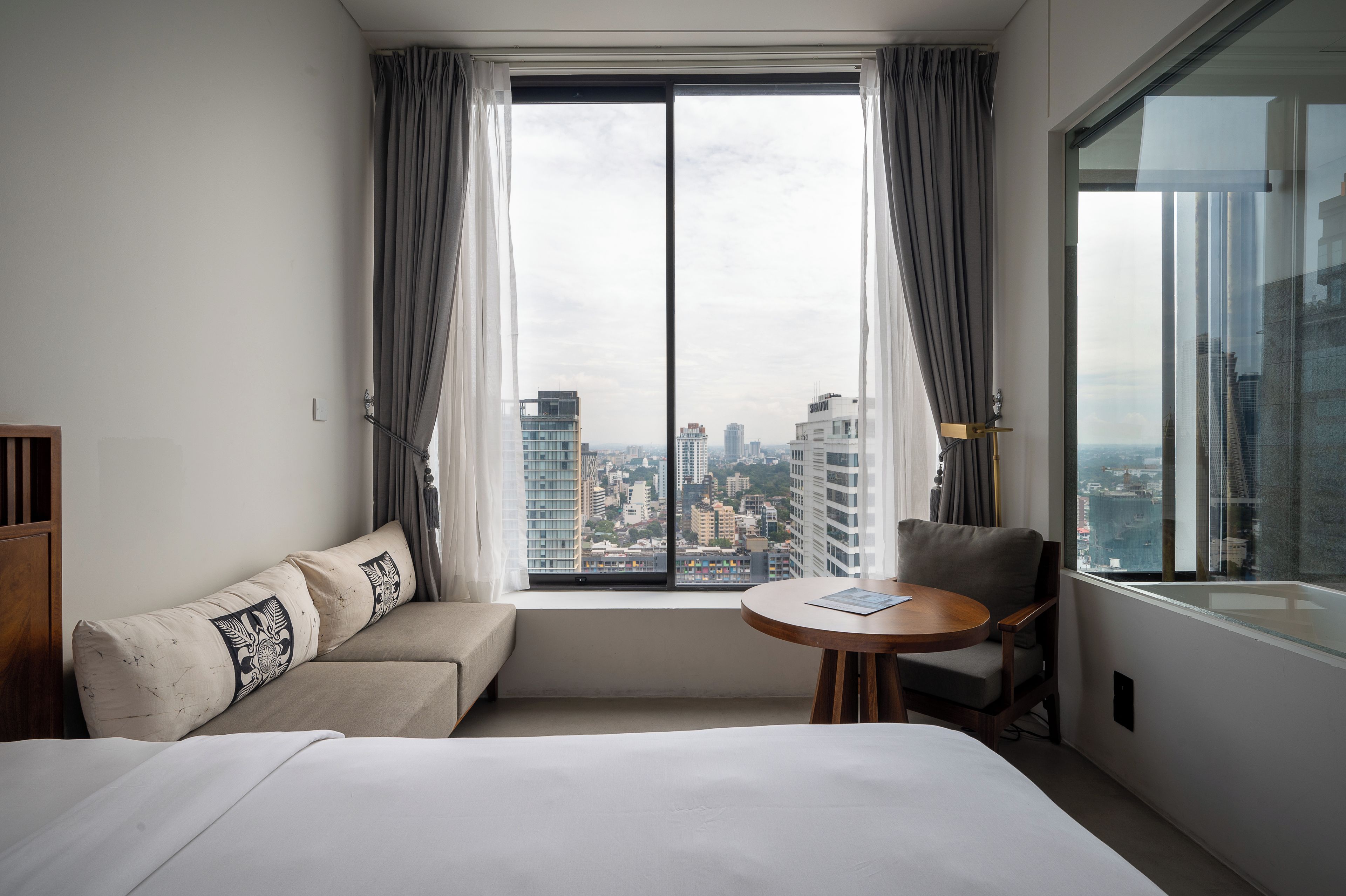 Ein Hotelzimmer mit großem Fenster, einem Bett, einer Couch und einem kleinen Tisch.