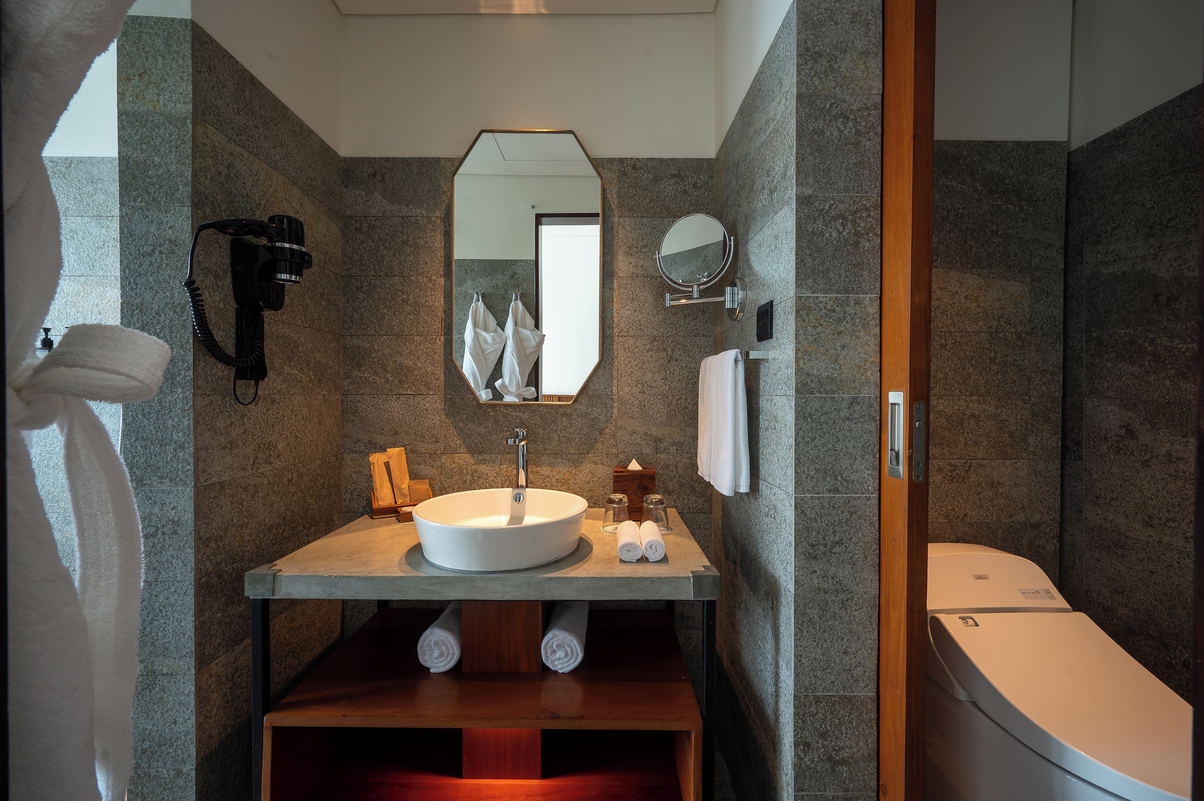Une salle de bain équipée d’un lavabo, d’un miroir, d’un porte-serviettes et de toilettes.