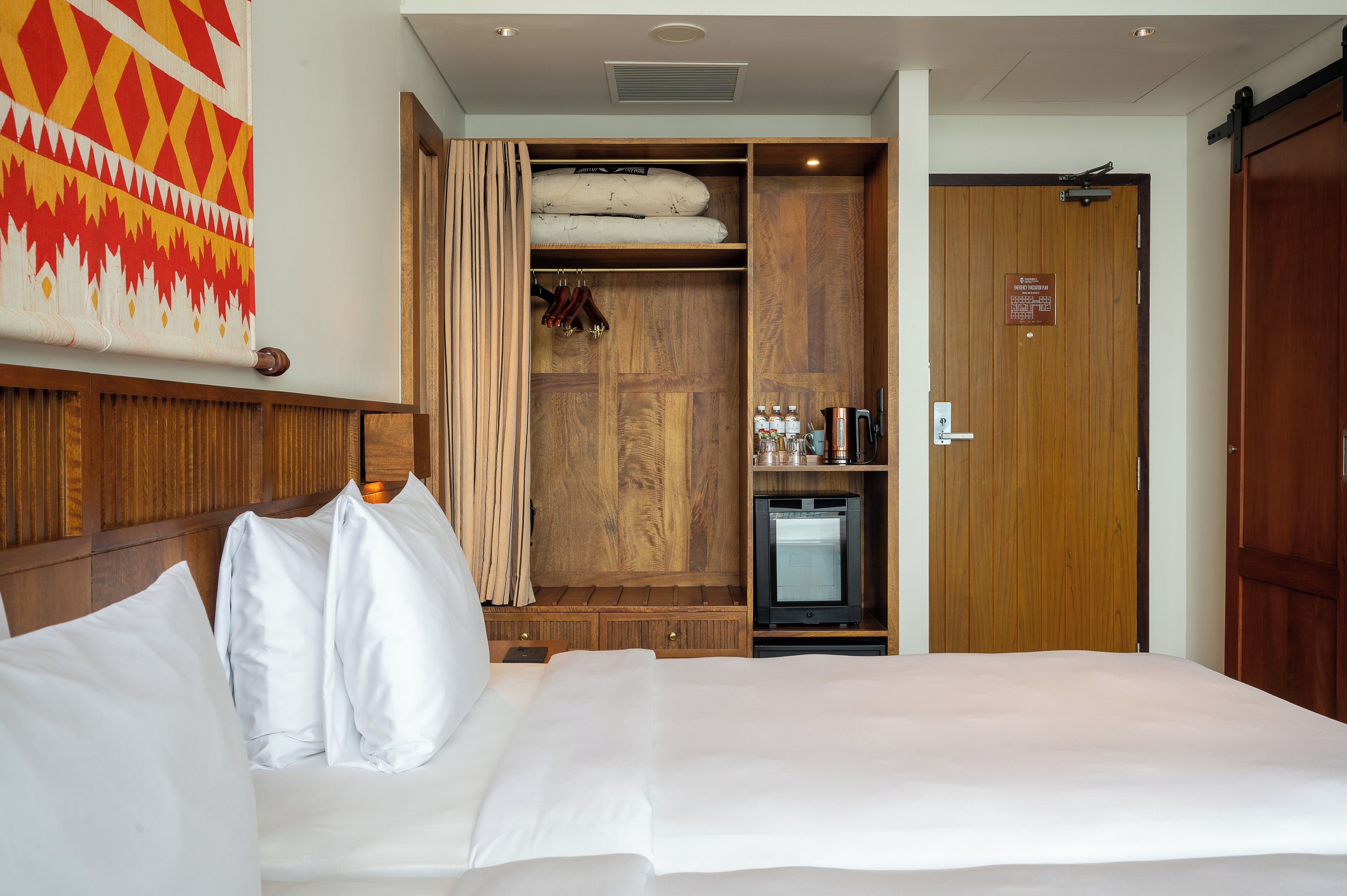 Une chambre d’hôtel équipée d’un lit, d’une armoire, d’un mini-bar et d’une télévision.