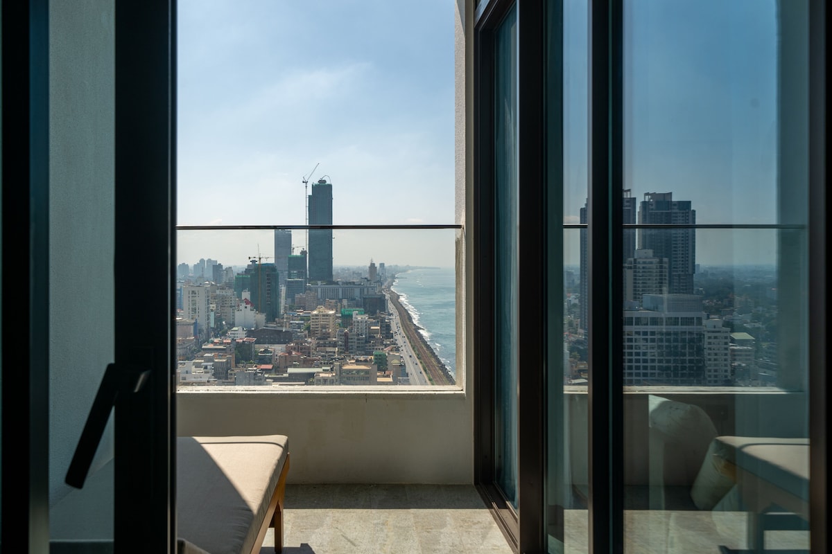 Un balcon avec vue sur la ville, un banc et une porte vitrée.