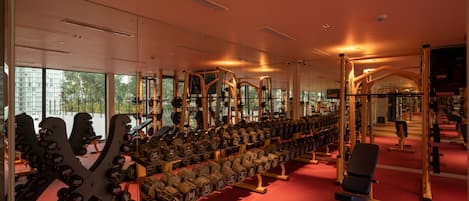 Une salle de sport équipée de matériel de musculation et de miroirs.