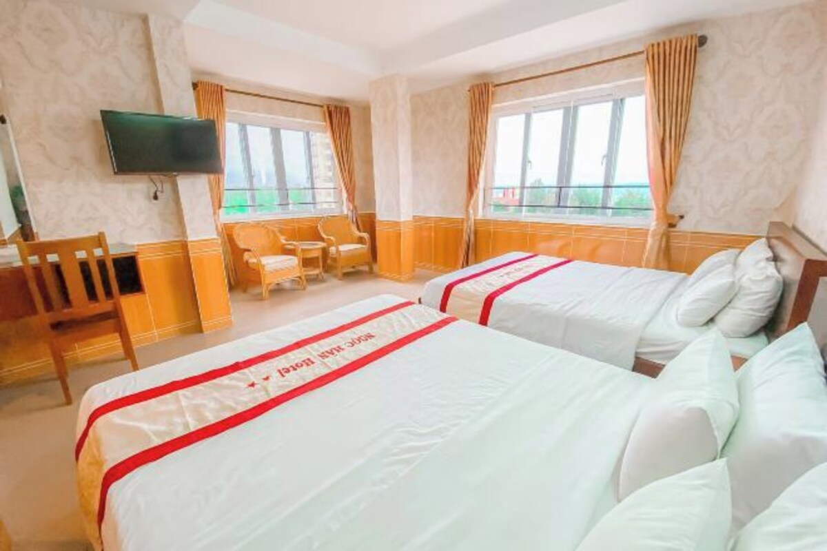 Une chambre d’hôtel avec deux lits, une télévision, un bureau et une chaise.