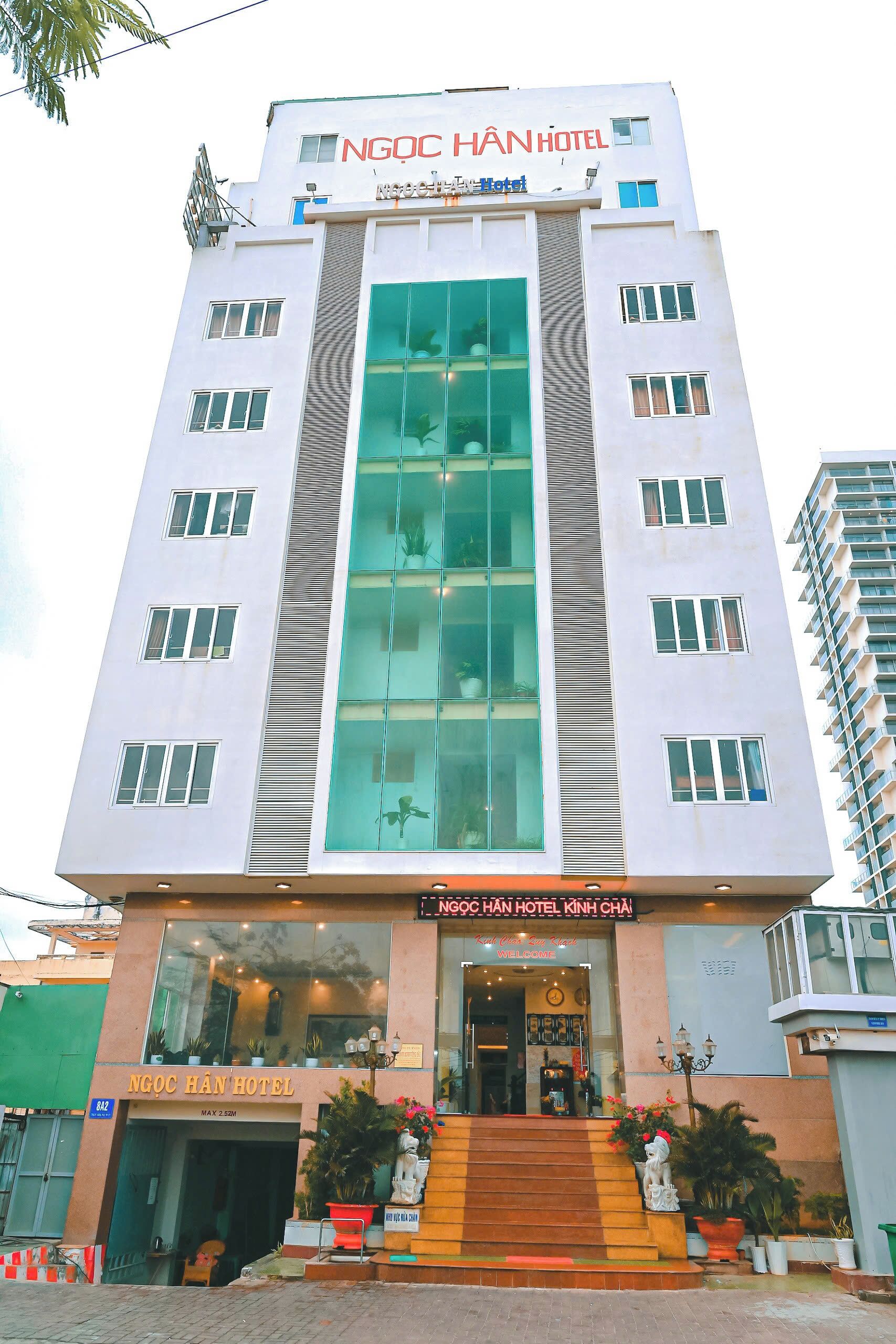 A modern hotel building with a prominent entrance, multiple windows, and a sign reading "NGOC HAN HOTEL".