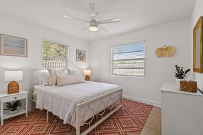 A bedroom with a bed, bedside tables, a ceiling fan, and a window with blinds.