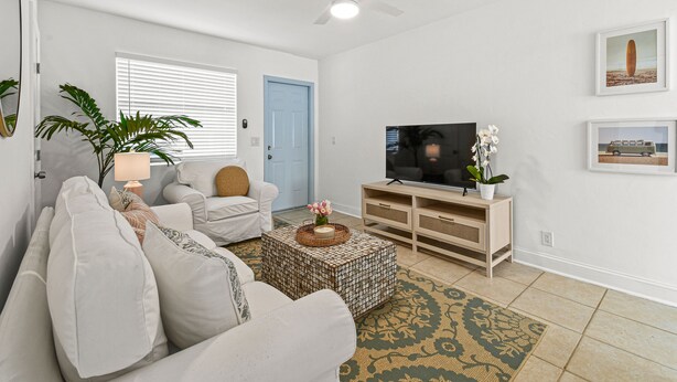 A living room with a sofa, a coffee table, a TV, and a door. - "Sunflower Cottage Apt" 2/1 (West Palm Beach)