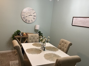 Cozy dining area with a round clock, inspirational quote, and tufted chairs.