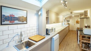Una cocina moderna con tragaluz, una isla grande y vista a un castillo a través de una ventana.